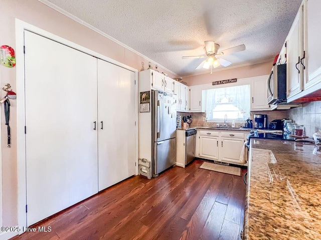 kitchen with a ceiling fan, a sink, white cabinetry, stainless steel appliances, and dark wood-style flooring