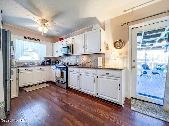 kitchen with dark wood-style floors, ceiling fan, stainless steel appliances, white cabinets, and backsplash