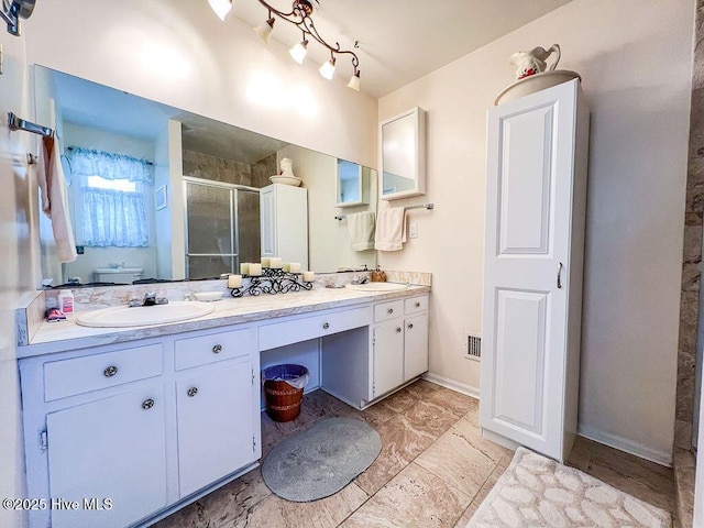 bathroom with a shower stall, double vanity, visible vents, and a sink