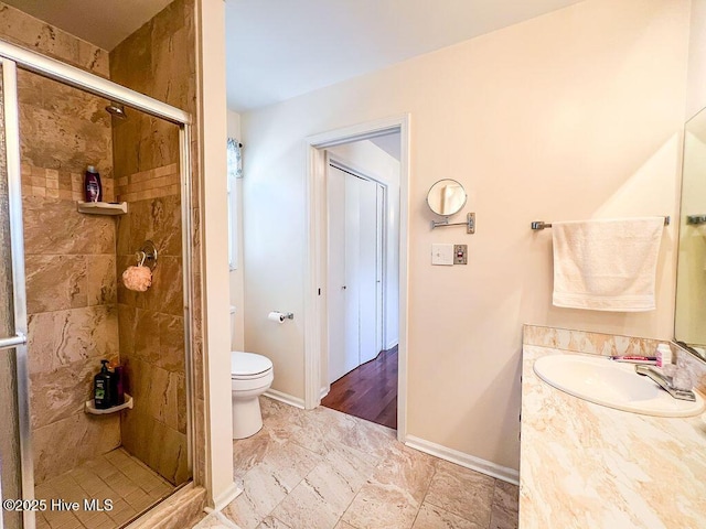 bathroom with vanity, toilet, baseboards, and a stall shower