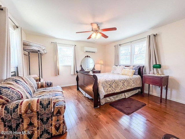 bedroom featuring baseboards, wood-type flooring, a ceiling fan, and a wall unit AC