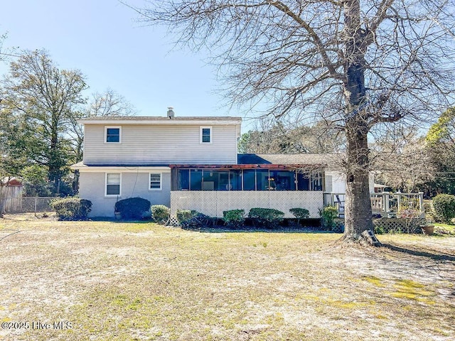 rear view of house with fence, a yard, and a sunroom