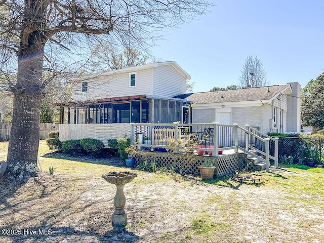 back of house featuring a wooden deck, fence, an attached garage, and a sunroom