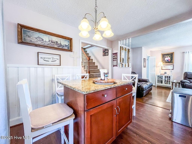 kitchen featuring light stone countertops, a chandelier, open floor plan, wainscoting, and dark wood-style flooring