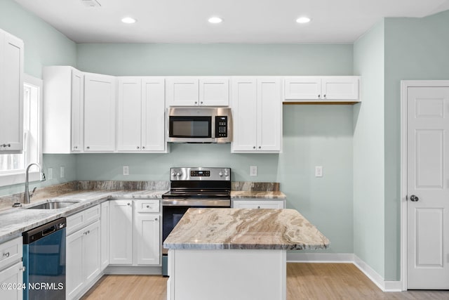 kitchen with light stone countertops, a kitchen island, a sink, white cabinets, and appliances with stainless steel finishes