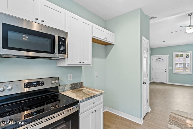 kitchen with light wood finished floors, baseboards, stainless steel appliances, white cabinetry, and a ceiling fan