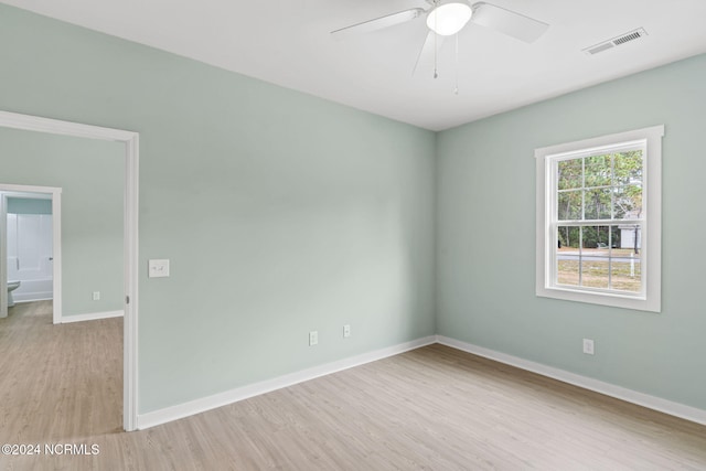 empty room featuring light wood finished floors, visible vents, baseboards, and a ceiling fan