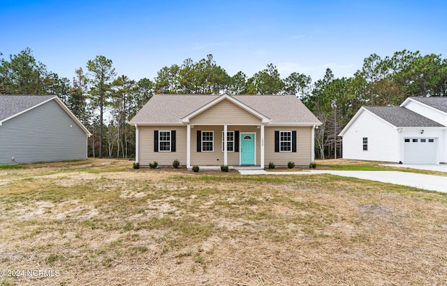 ranch-style home featuring a porch, driveway, a front lawn, and roof with shingles