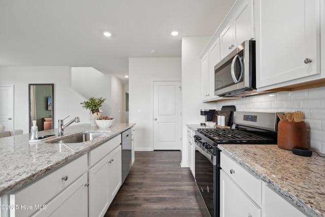 kitchen with a sink, decorative backsplash, white cabinets, stainless steel appliances, and dark wood-style flooring