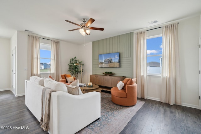 living area featuring visible vents, baseboards, ceiling fan, and wood finished floors