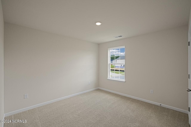 empty room with visible vents, light carpet, and baseboards