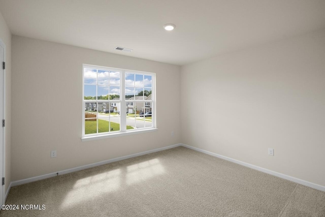 carpeted spare room featuring baseboards and visible vents