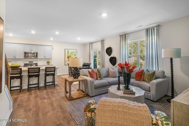 living area with recessed lighting, baseboards, and wood finished floors