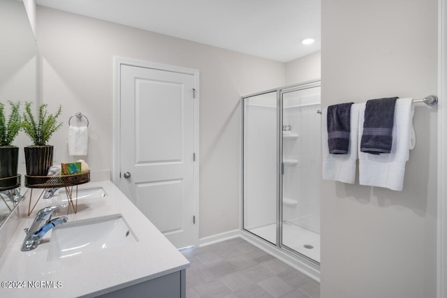 bathroom with a sink, a stall shower, double vanity, and tile patterned floors