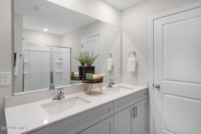 full bathroom with a sink, a shower stall, and double vanity