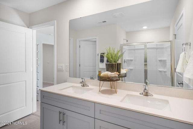 full bath with double vanity, visible vents, a stall shower, and a sink