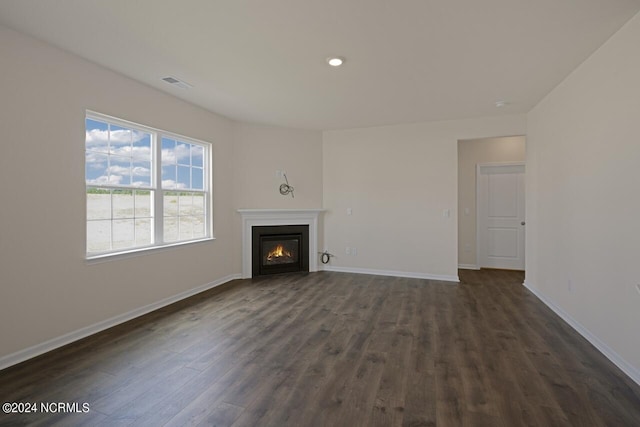 unfurnished living room with visible vents, baseboards, recessed lighting, a glass covered fireplace, and dark wood-style flooring