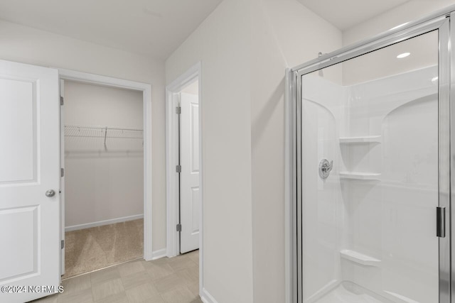 bathroom with baseboards, a stall shower, and a spacious closet