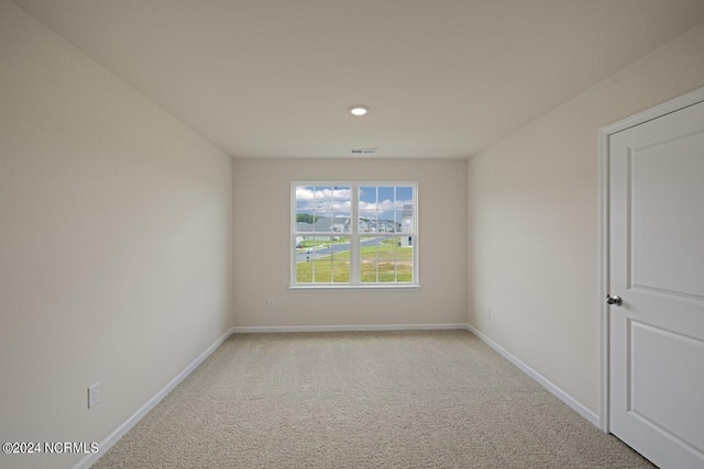 spare room featuring visible vents, baseboards, and light colored carpet