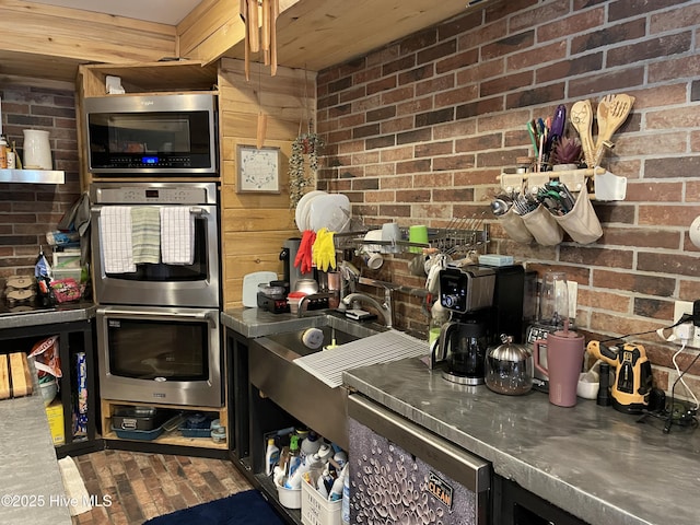 kitchen featuring stainless steel counters, brick wall, and stainless steel appliances