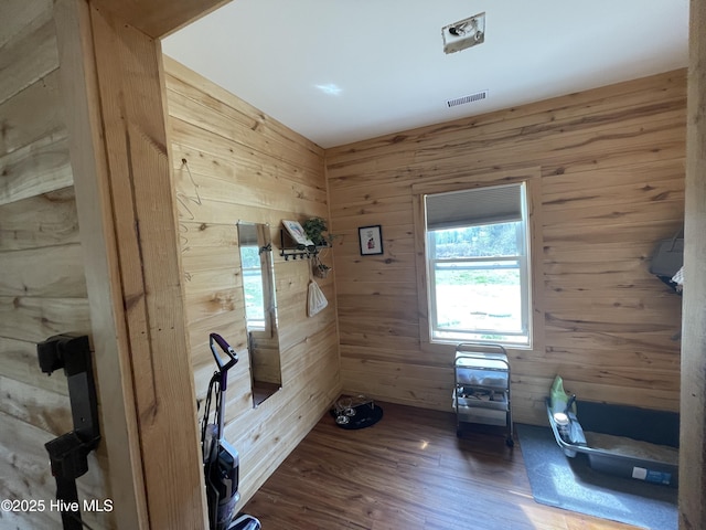 interior space with visible vents, wood finished floors, and wood walls