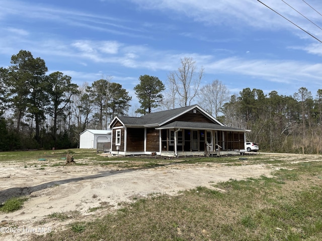 view of front of house featuring an outdoor structure, a sunroom, a shed, and dirt driveway