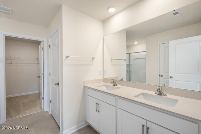 bathroom with a shower stall, a spacious closet, visible vents, and a sink