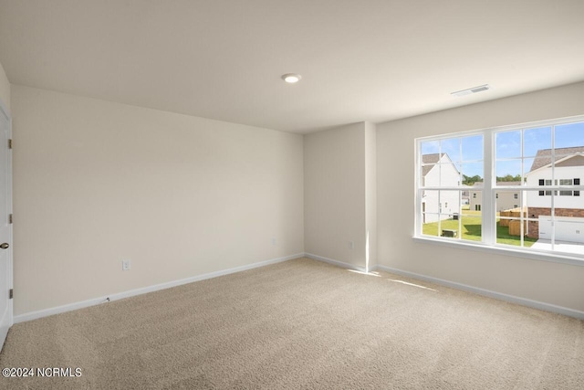 carpeted spare room with visible vents and baseboards