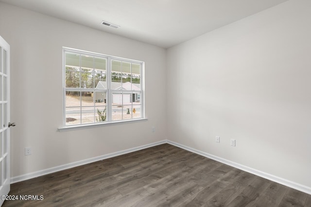 spare room featuring dark wood finished floors, baseboards, and visible vents