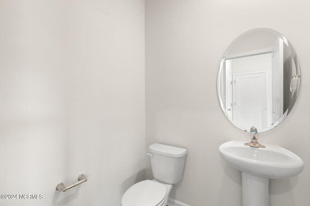 half bathroom with baseboards and toilet