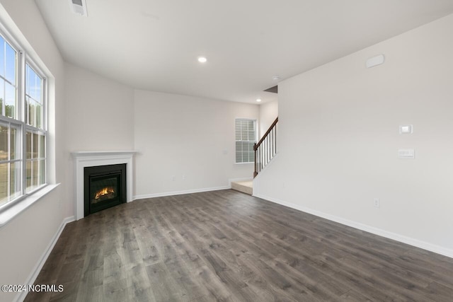 unfurnished living room with visible vents, dark wood-type flooring, baseboards, recessed lighting, and a glass covered fireplace