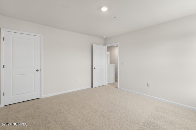 unfurnished bedroom featuring light colored carpet and baseboards