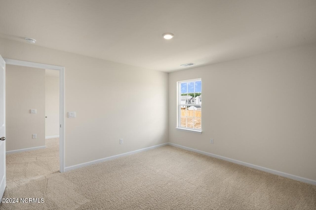 empty room featuring light carpet, visible vents, and baseboards