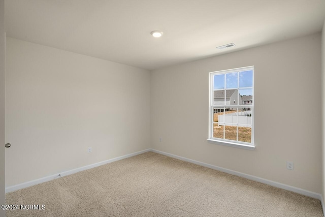 spare room with carpet flooring, baseboards, and visible vents