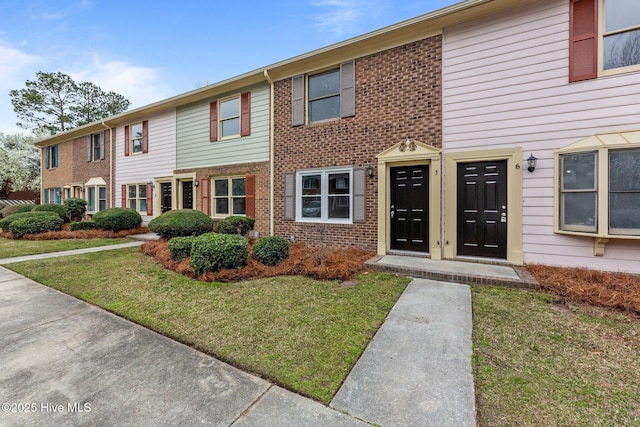 view of property featuring brick siding and a front lawn