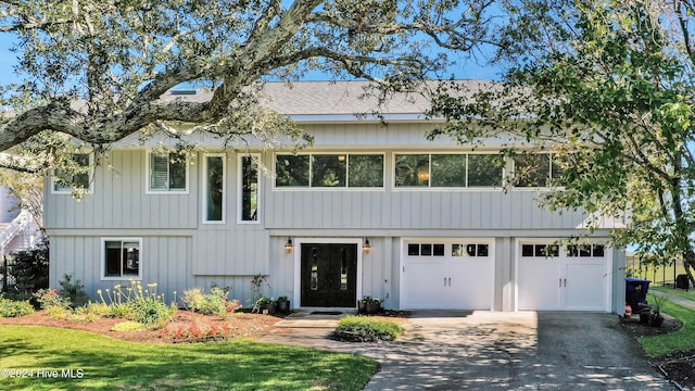 view of front of house featuring a front lawn, an attached garage, and driveway