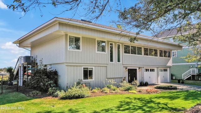 view of front of house featuring cooling unit, fence, driveway, a front lawn, and a garage