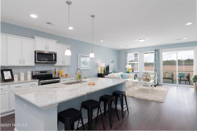 kitchen with visible vents, dark wood finished floors, a kitchen breakfast bar, stainless steel appliances, and a sink