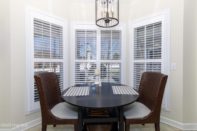 dining area featuring tile patterned floors, baseboards, and a chandelier