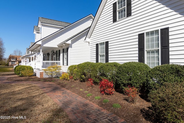 view of side of home featuring covered porch