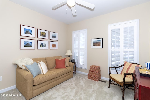 living room featuring light colored carpet, baseboards, and a ceiling fan