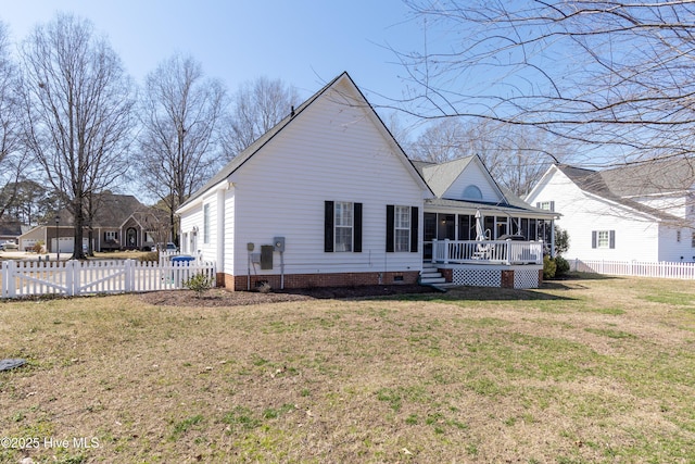 rear view of property featuring a lawn, a fenced backyard, and a sunroom