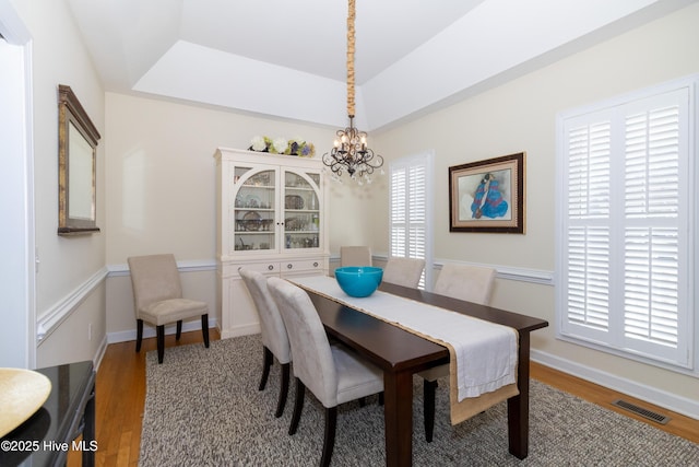 dining area featuring a notable chandelier, wood finished floors, visible vents, and a wealth of natural light