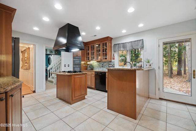 kitchen featuring stacked washing maching and dryer, island exhaust hood, black dishwasher, a wealth of natural light, and a center island