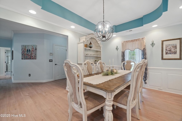 dining room with crown molding, a wainscoted wall, recessed lighting, light wood-style flooring, and a notable chandelier