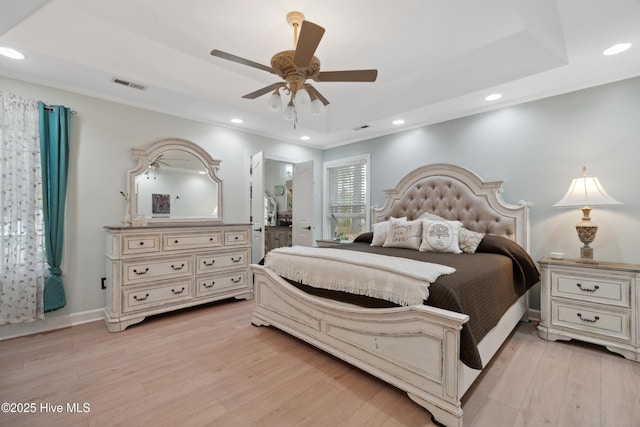 bedroom with recessed lighting, visible vents, light wood-style flooring, and a raised ceiling