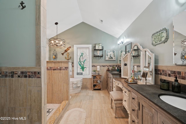 full bath with visible vents, a freestanding tub, a sink, tile walls, and double vanity