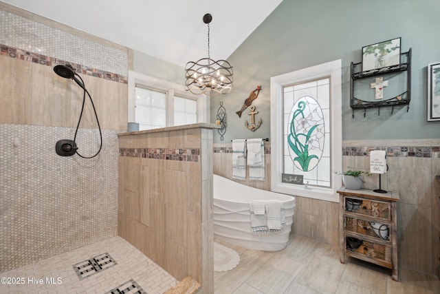 full bath with tile walls, a notable chandelier, lofted ceiling, and walk in shower