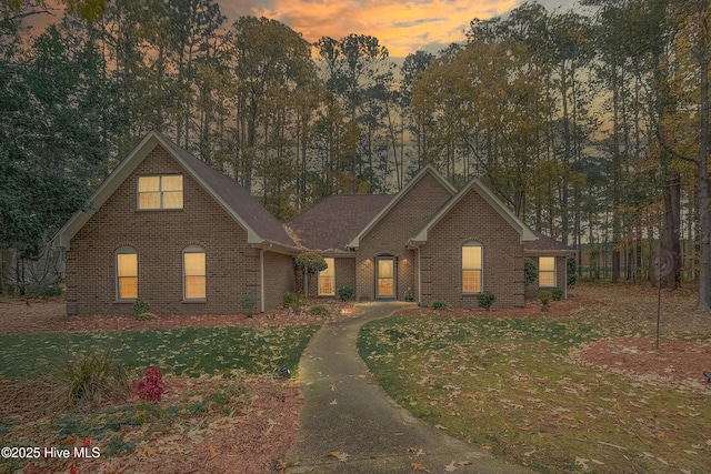 traditional home featuring a lawn and brick siding