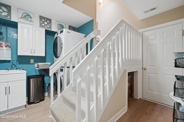 stairway with wood finished floors, visible vents, and stacked washer and clothes dryer